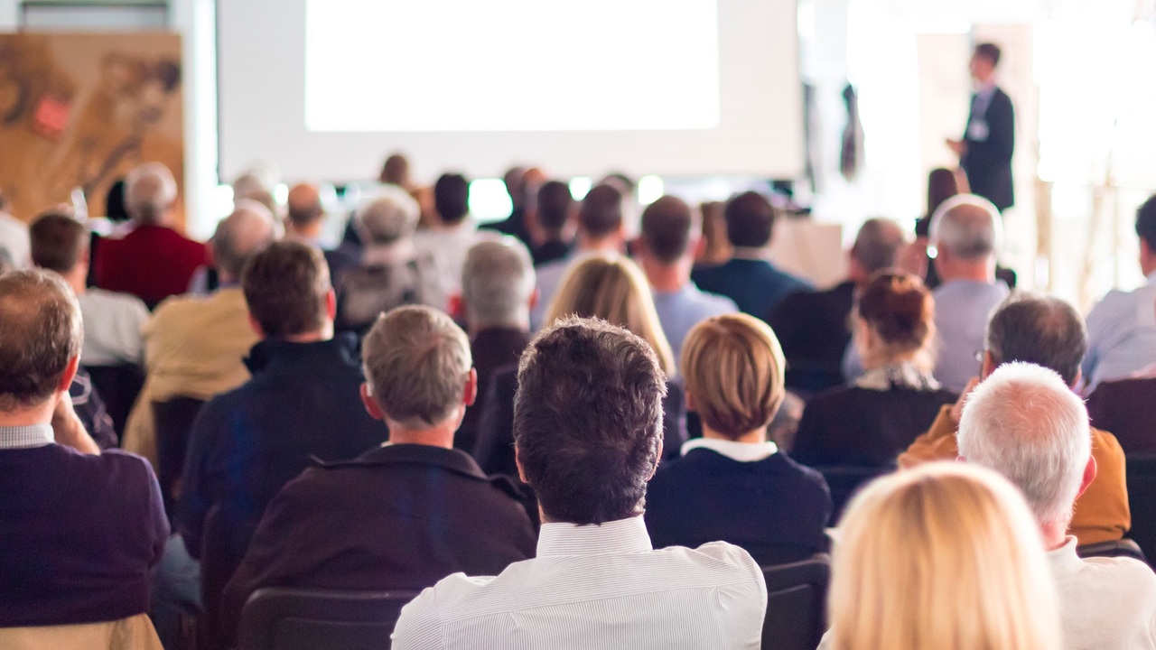 corporate-businessman-giving-presentation-large-audience