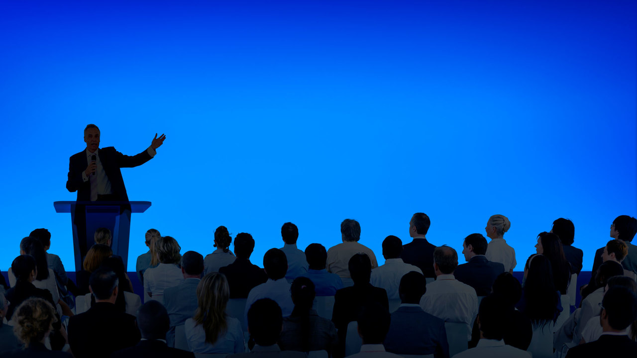 corporate-businessman-giving-presentation-large-audience